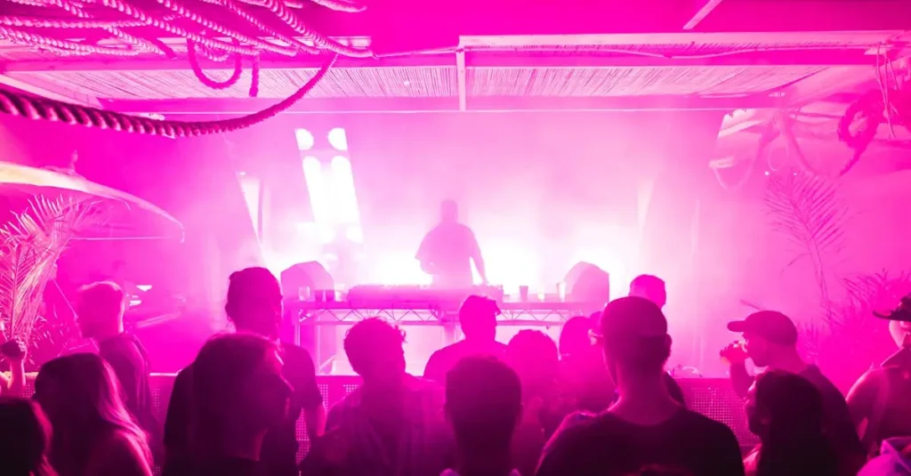 Energetic nightclub scene with DJ and crowd in vibrant pink lighting in North Fremantle, Australia.